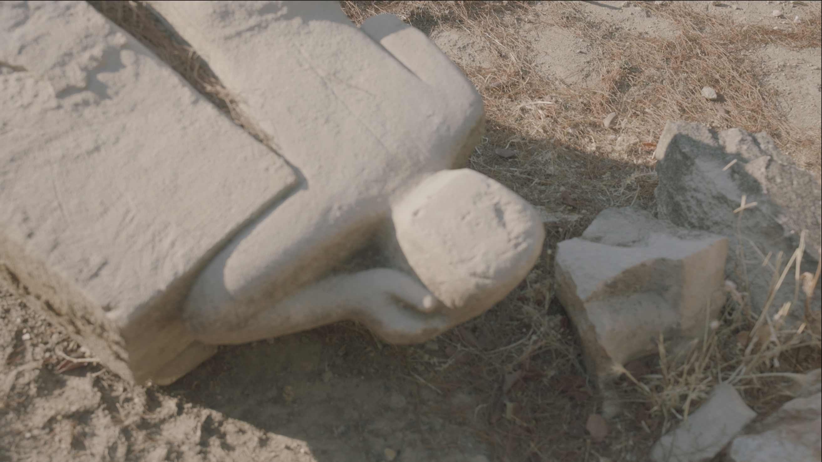 A stone sculpture lying face down one a rocky surface. 